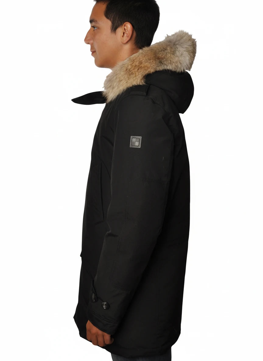 Modello indossa parka nero con cappuccio, pelliccia e toppe Woolrich