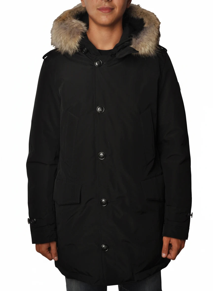 Modello indossa parka nero con cappuccio, pelliccia e toppe Woolrich