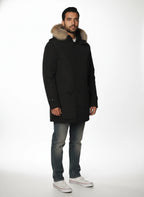Modello indossa parka nero con cappuccio, pelliccia e toppe Woolrich