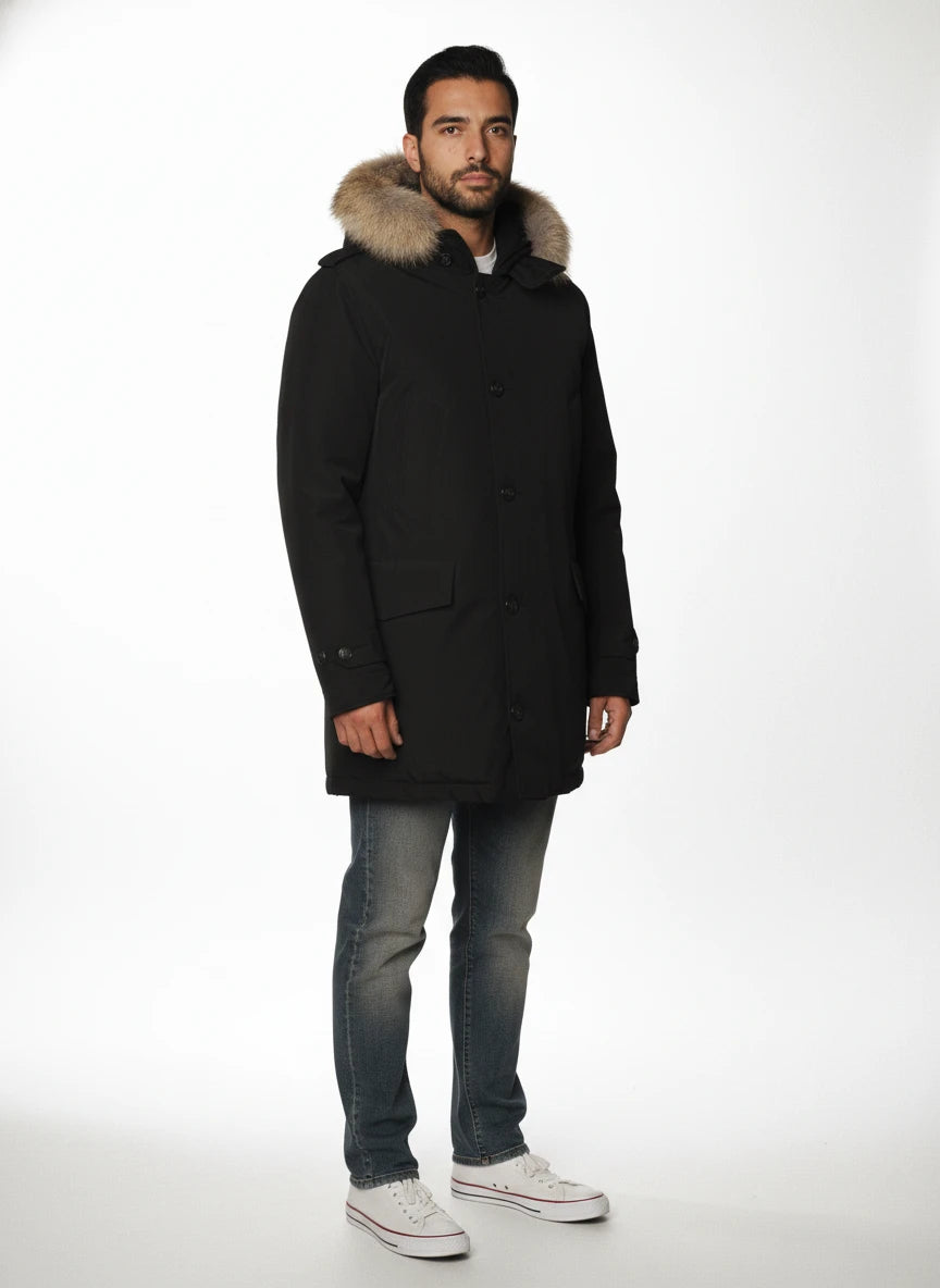 Modello indossa parka nero con cappuccio, pelliccia e toppe Woolrich