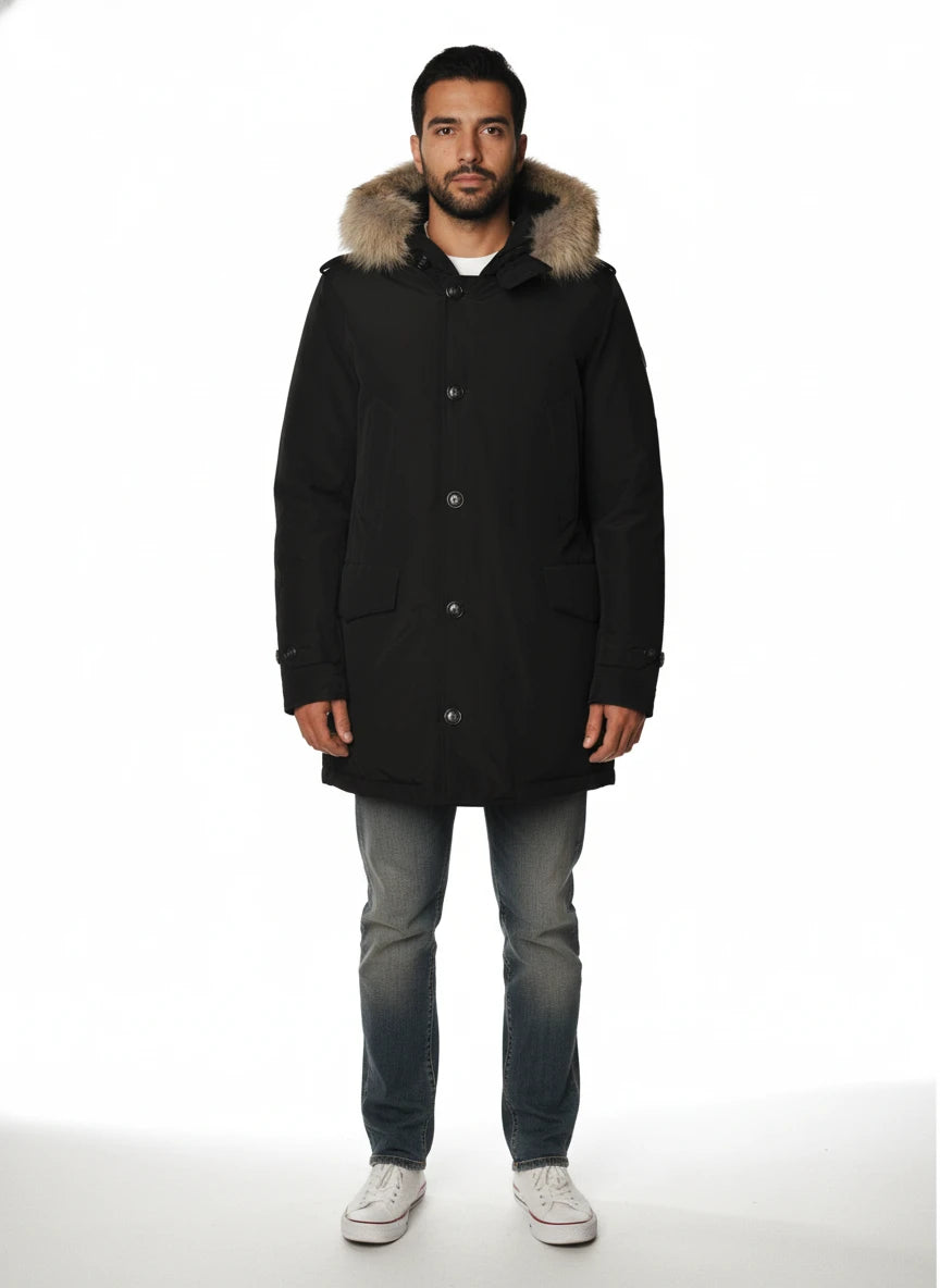 Modello indossa parka nero con cappuccio, pelliccia e toppe Woolrich