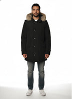 Modello indossa parka nero con cappuccio, pelliccia e toppe Woolrich