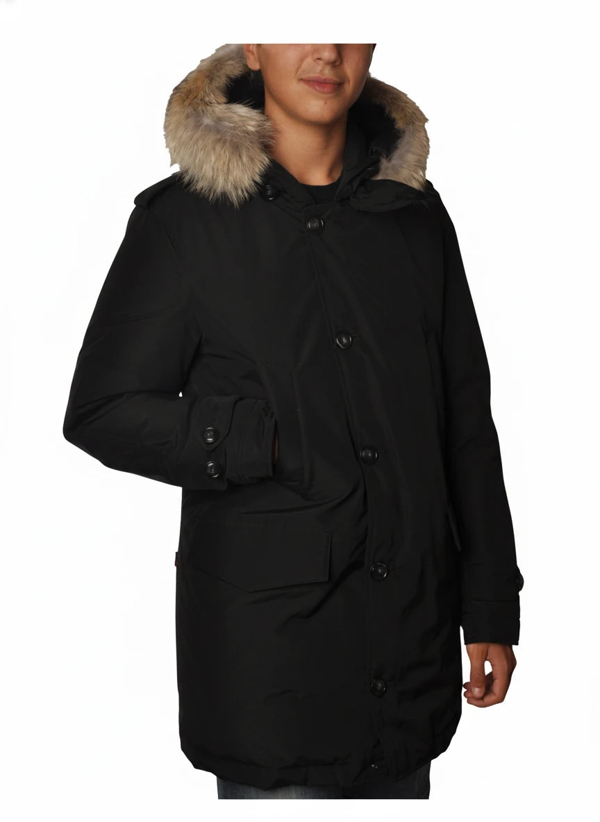 Modello indossa parka nero con cappuccio, pelliccia e toppe Woolrich