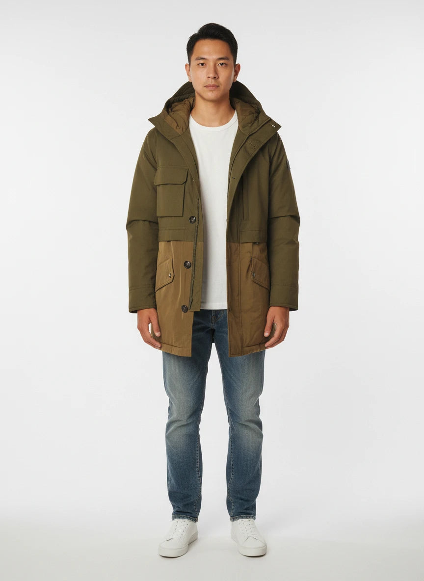 Modello indossa parka verde con cappuccio e tasca Woolrich in tessuto tecnico