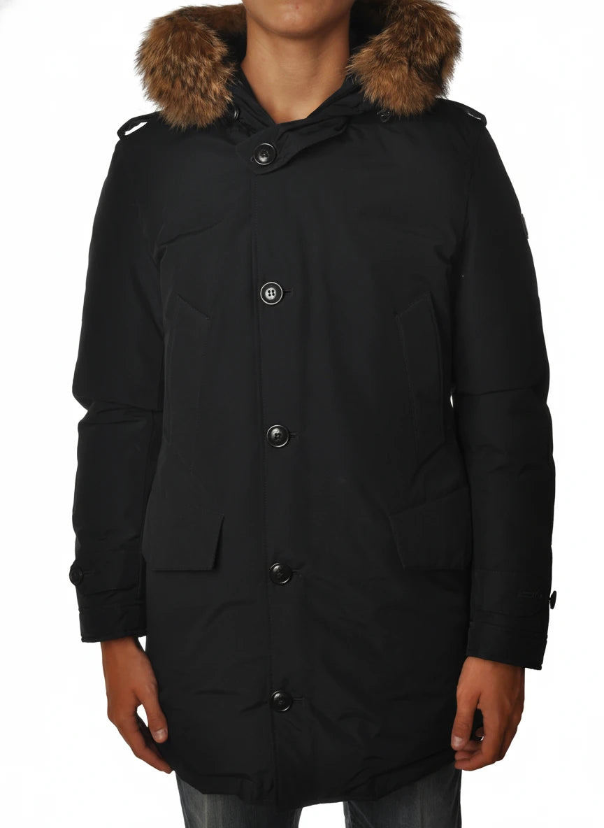 Modello indossa parka blu con cappuccio, pelliccia e toppe Woolrich