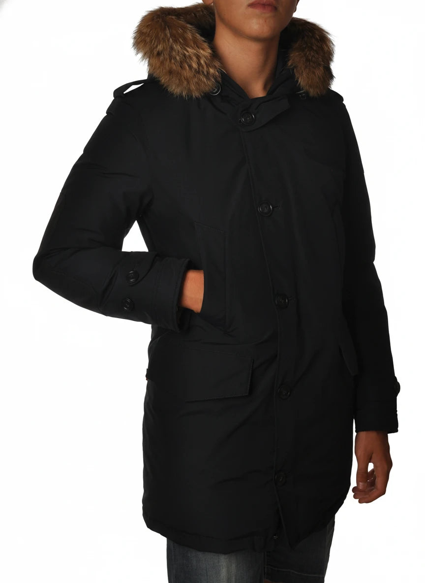 Modello indossa parka blu con cappuccio, pelliccia e toppe Woolrich