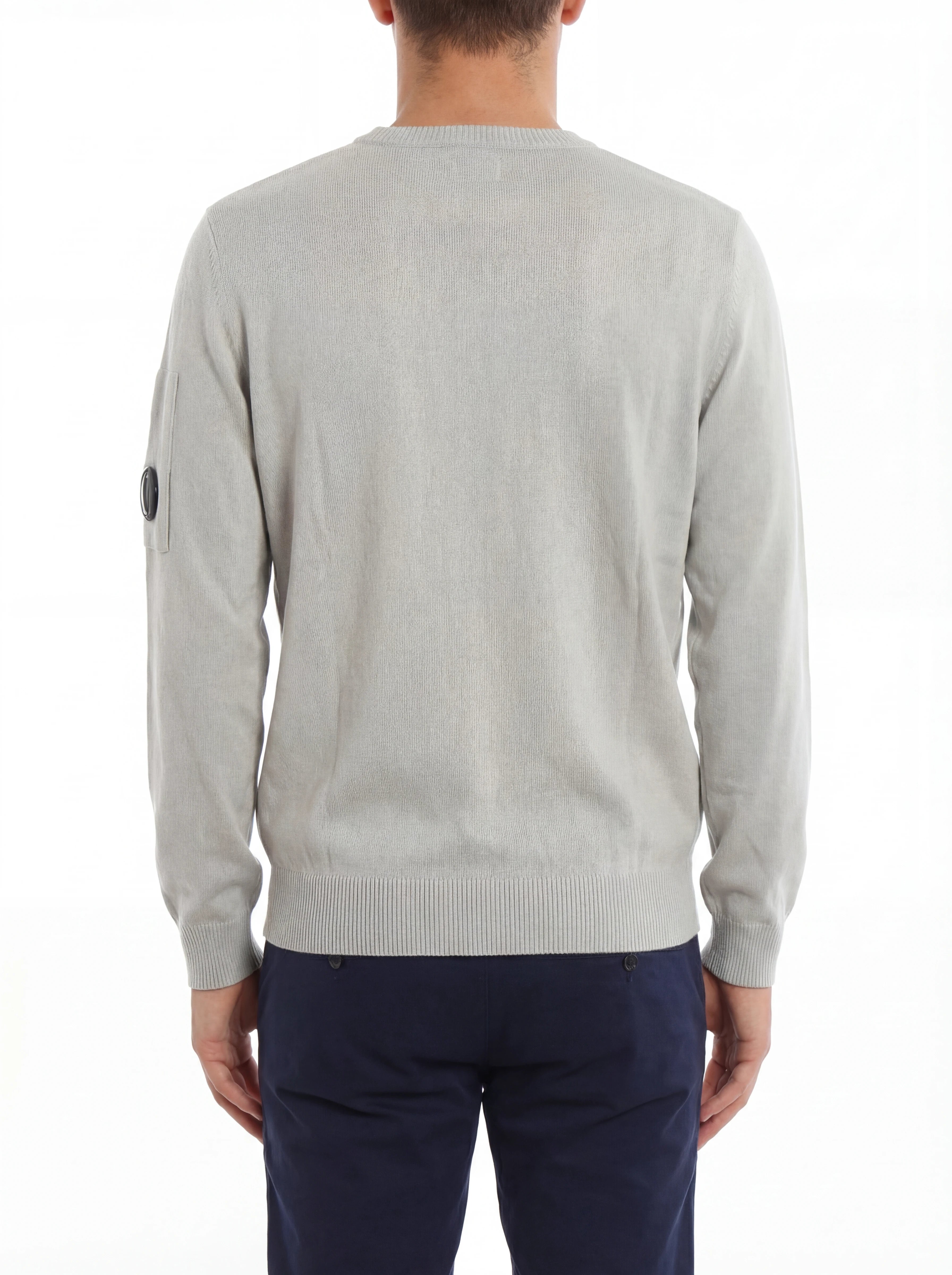 Vista da dietro, modello con maglia girocollo grigio perla taschino con lente taschino C.P. Company da uomo in cotone