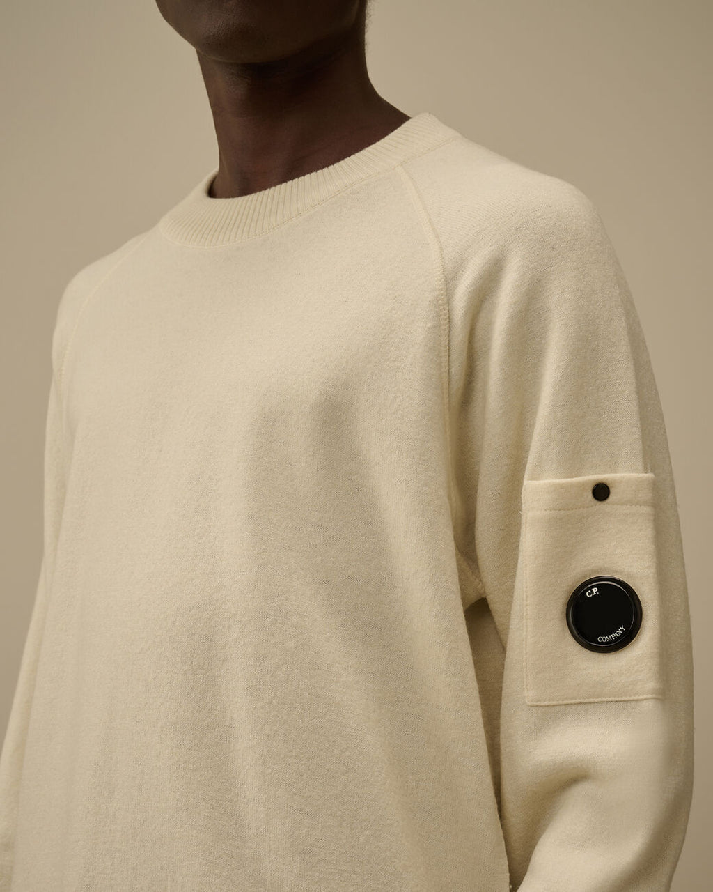 Vista da dietro, modello con maglia girocollo panna taschino con lente taschino C.P. Company da uomo in lana merino