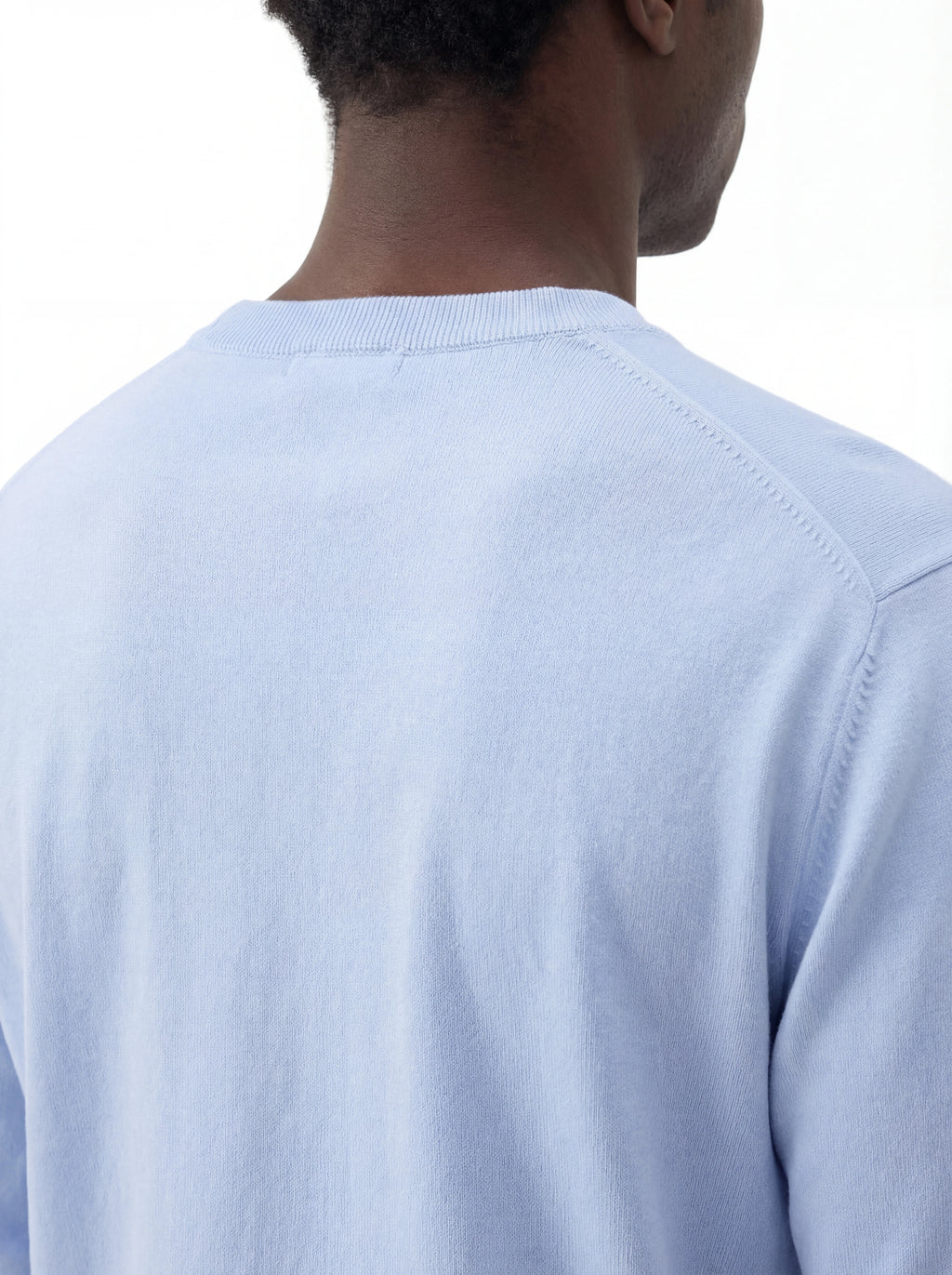 Vista da dietro, modello con maglia girocollo celeste C.P. Company da uomo