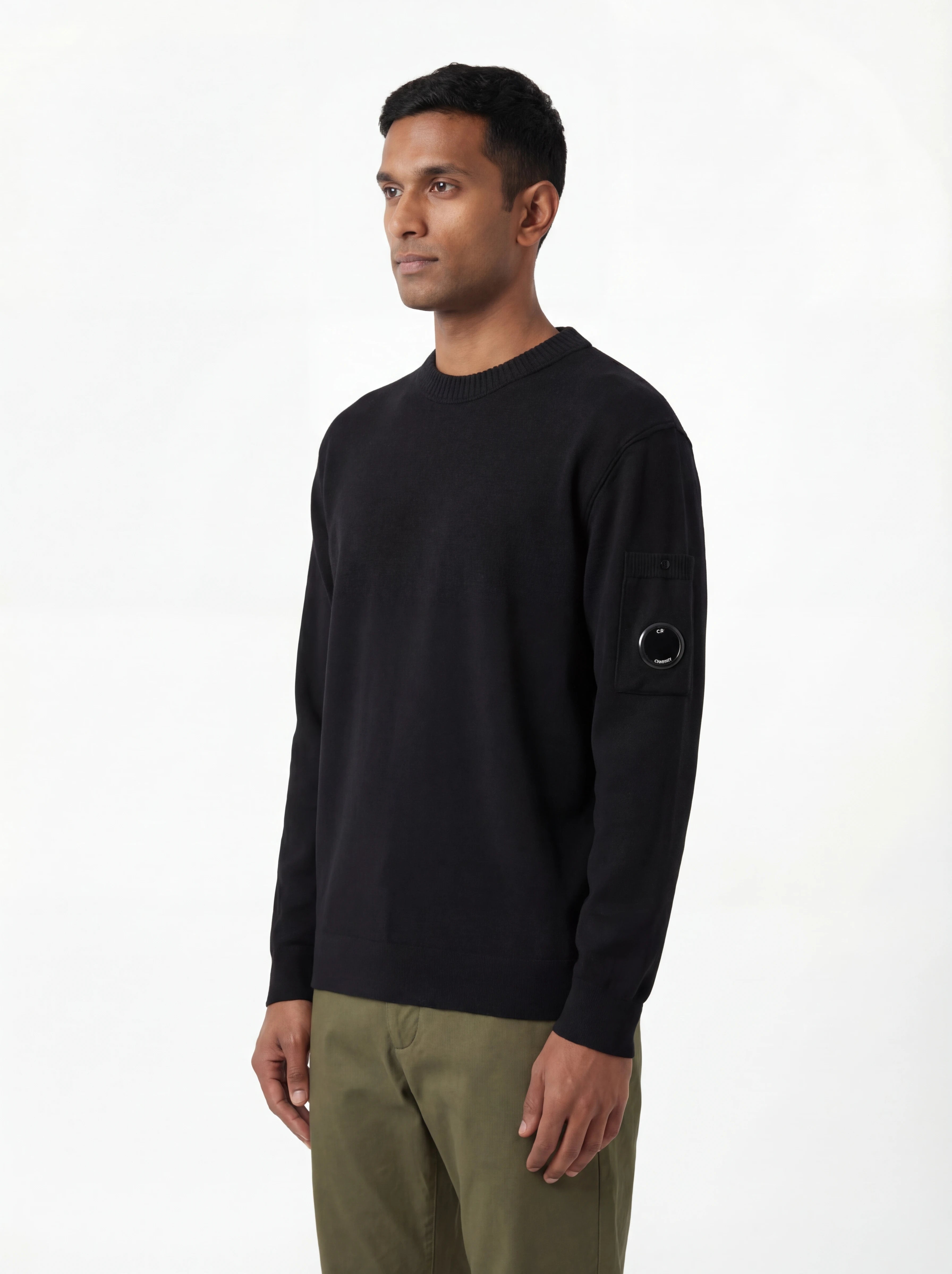 Modello indossa maglia girocollo nero taschino con lente taschino C.P. Company da uomo in cotone