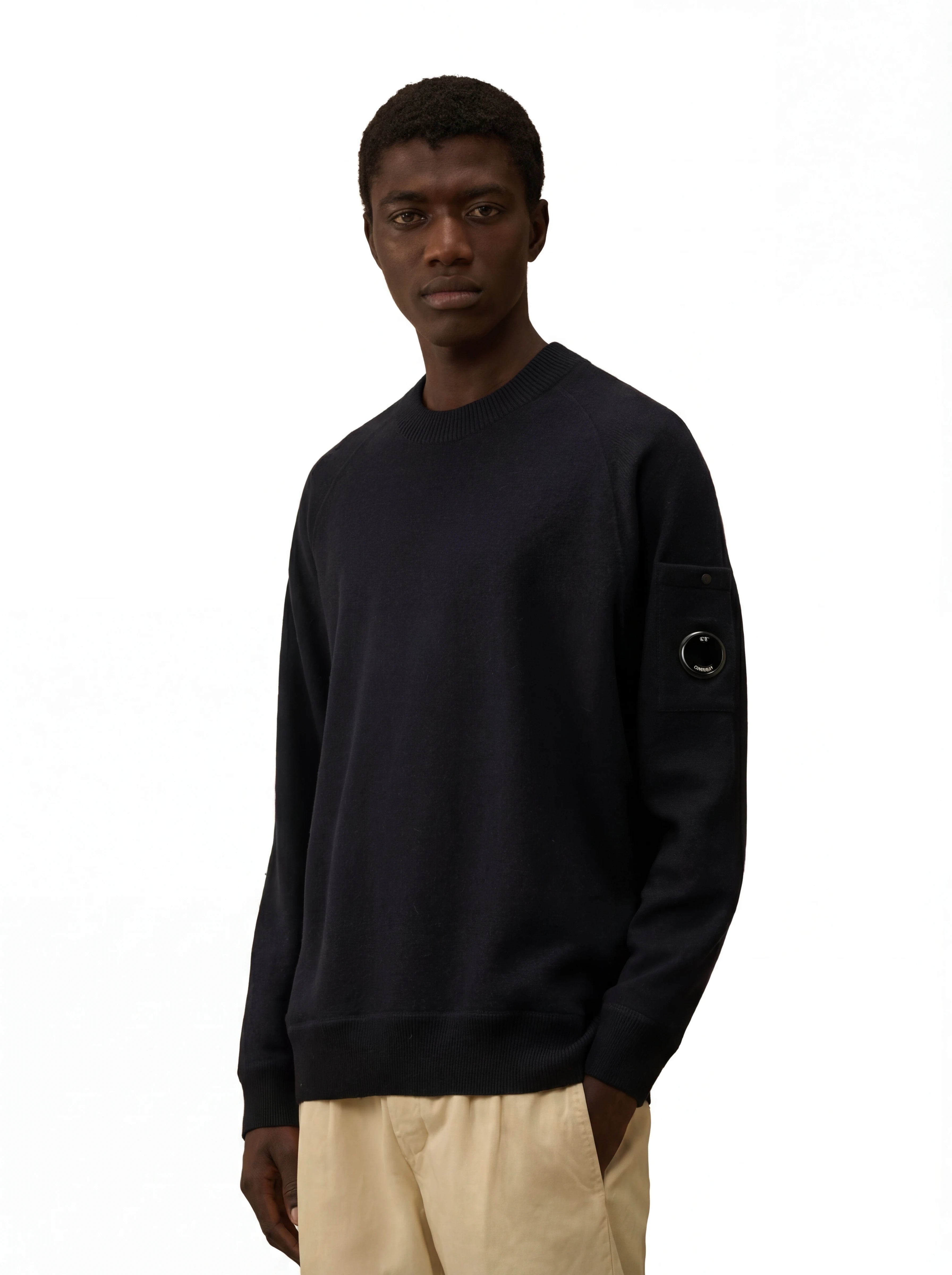 Modello indossa maglia girocollo blu taschino con lente taschino C.P. Company da uomo in lana merino