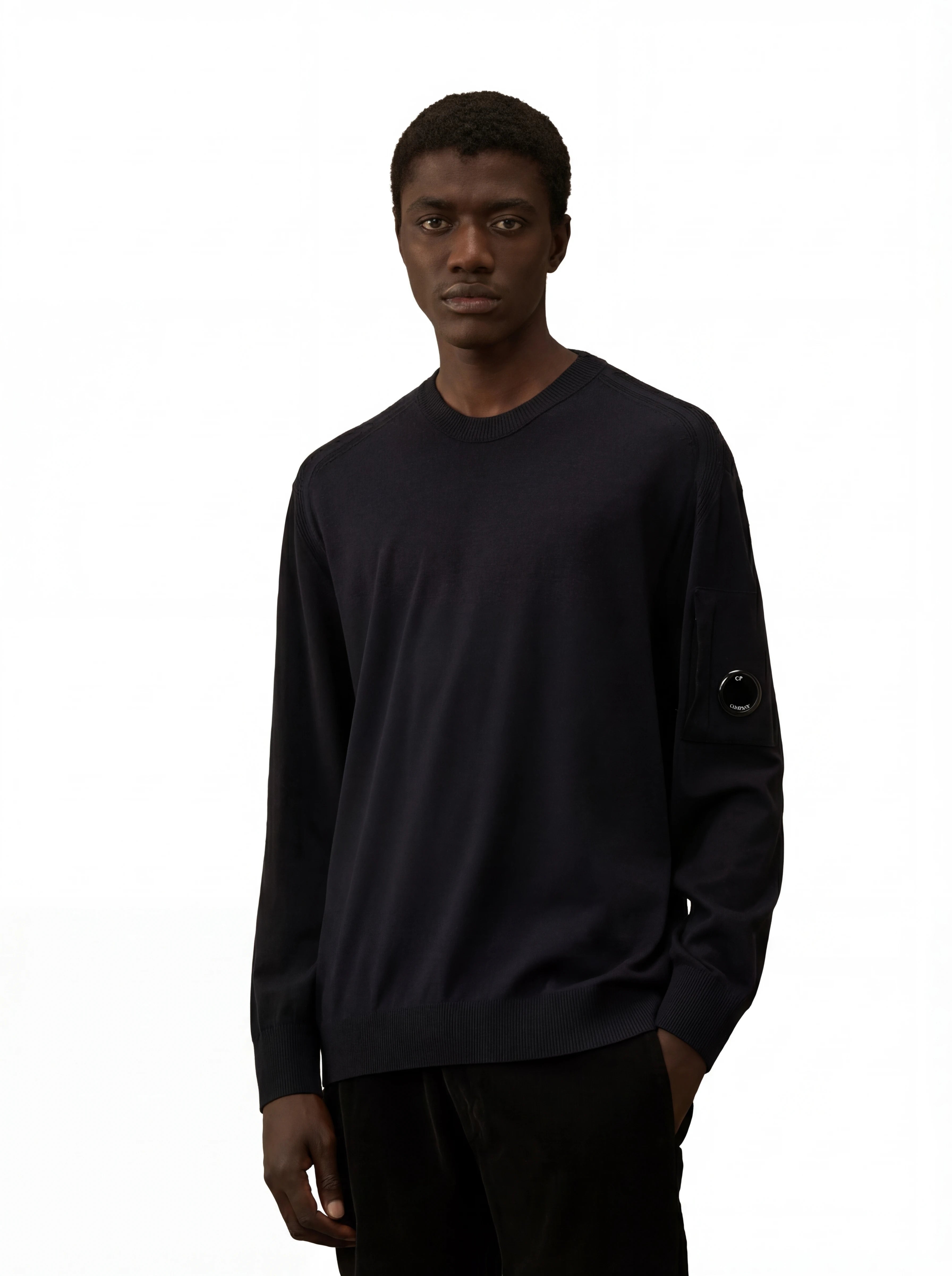 Modello indossa maglia girocollo blu taschino con lente taschino C.P. Company da uomo in lana merino extrafine